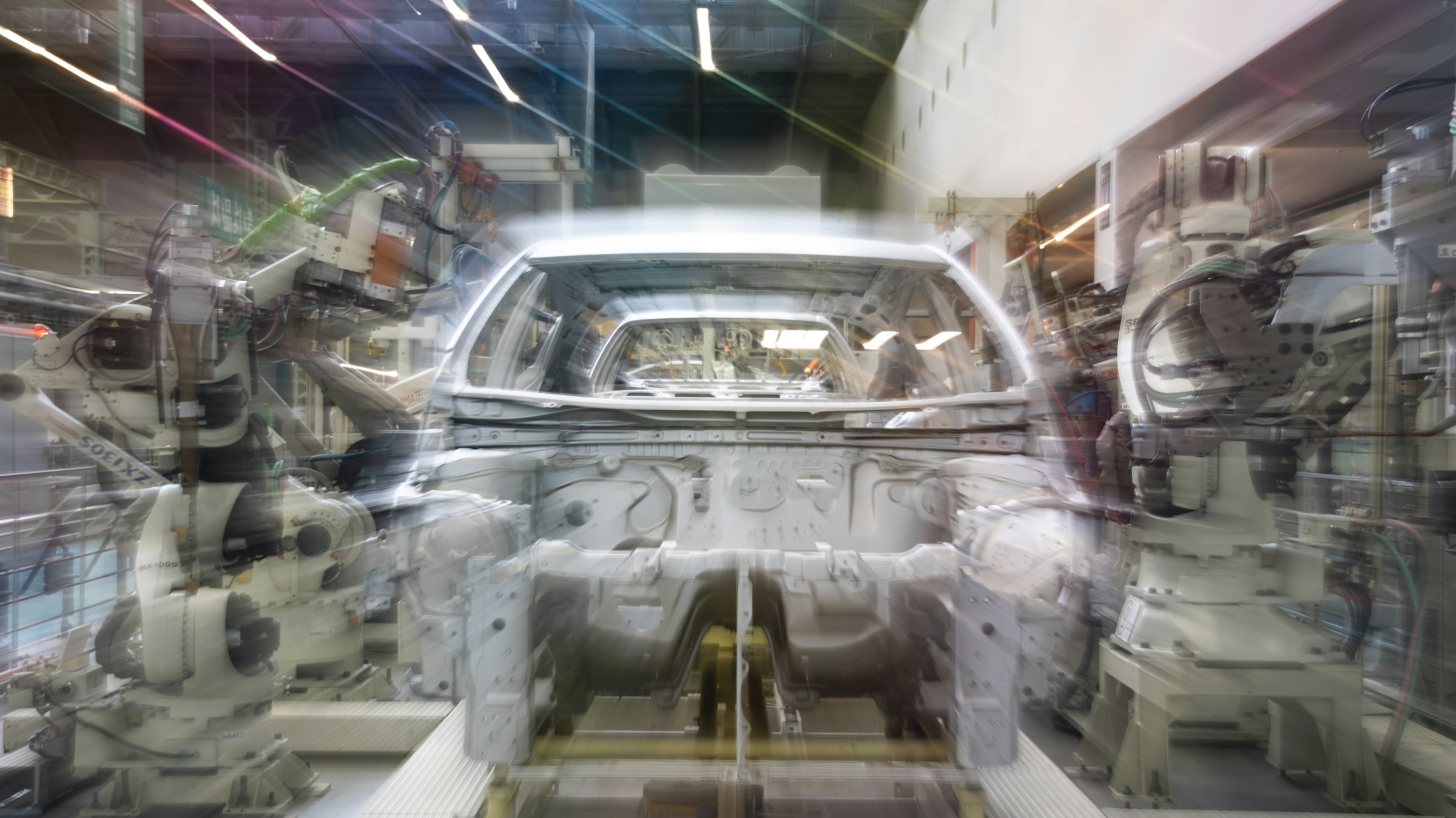 Brazos robóticos ensamblando una carrocería de coche en una línea de producción industrial